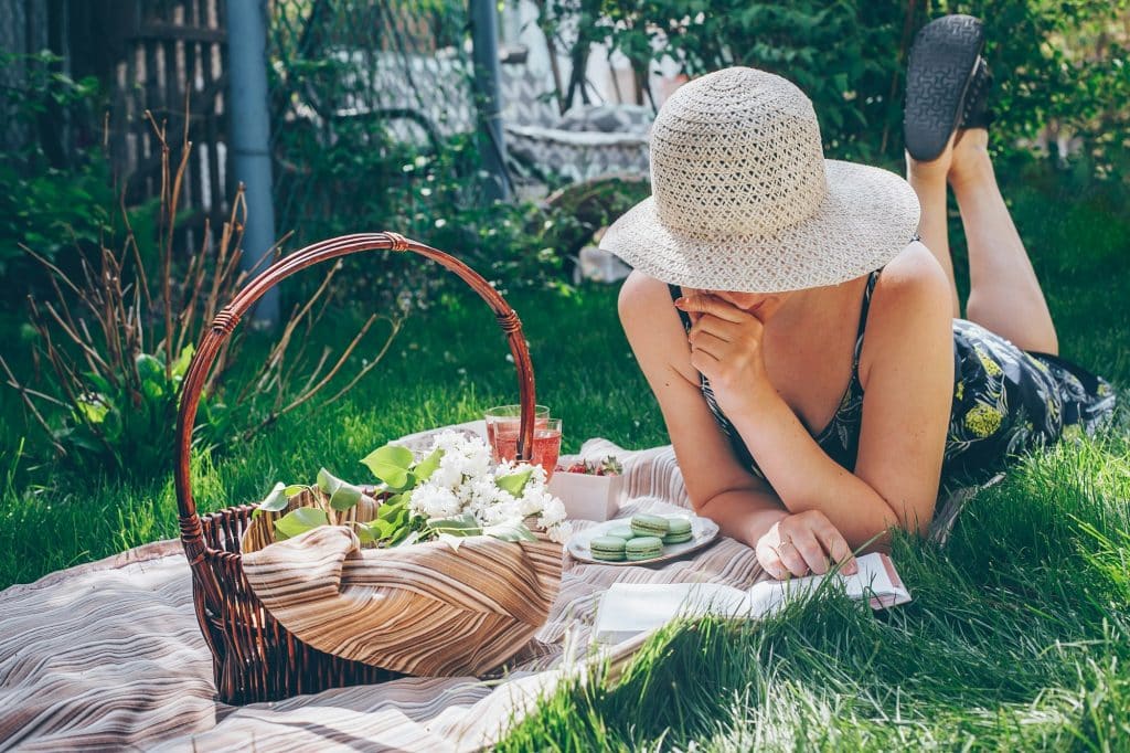 Young woman reading book lying on grass. Picnic